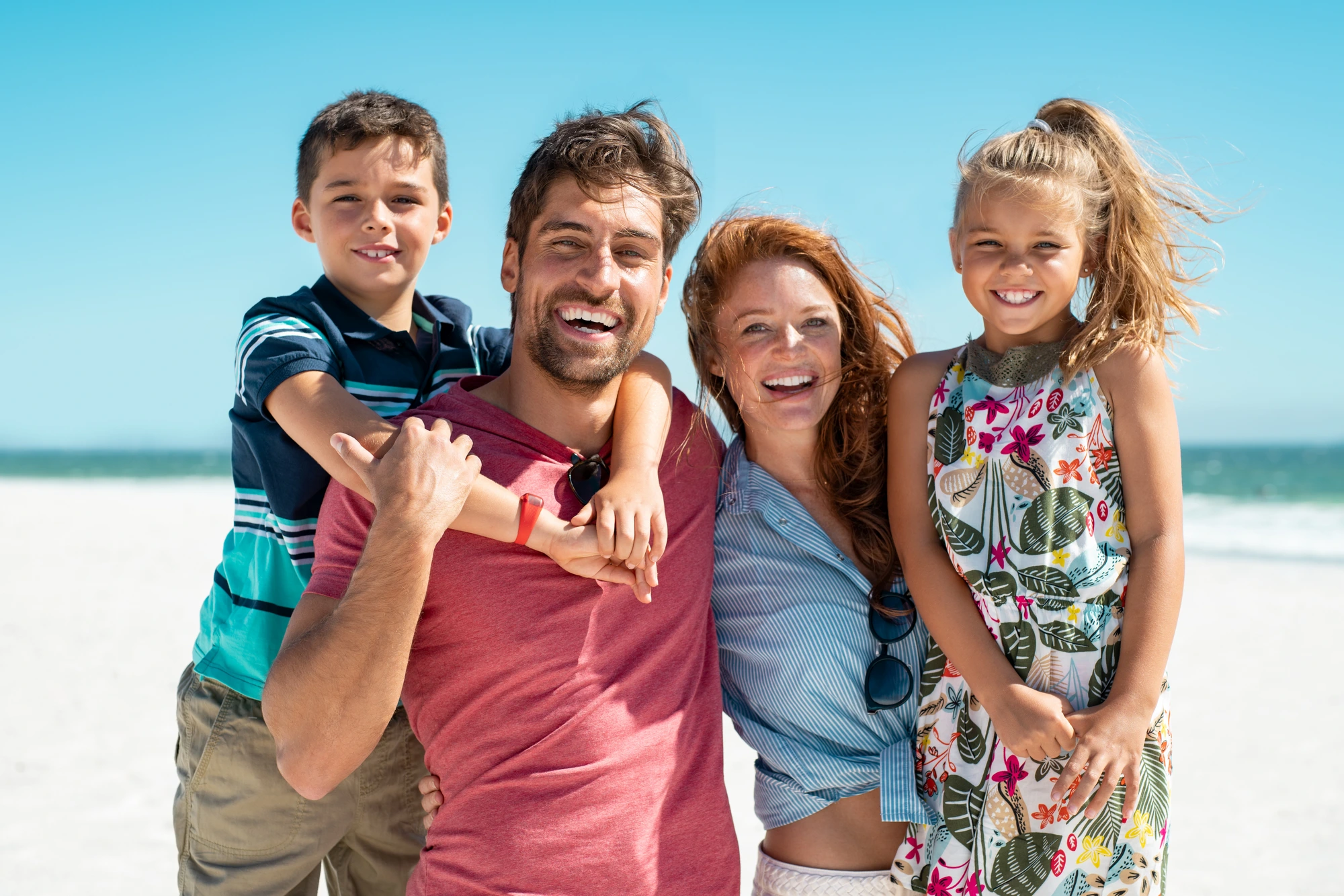 Family of four smiling at the beach