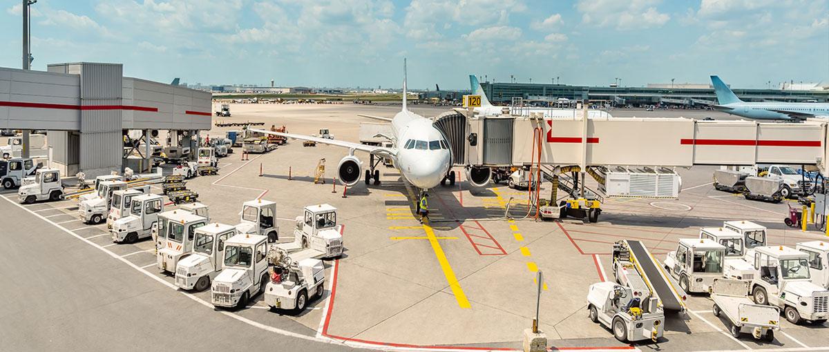 Airport apron with jet at gate and ground vehicles