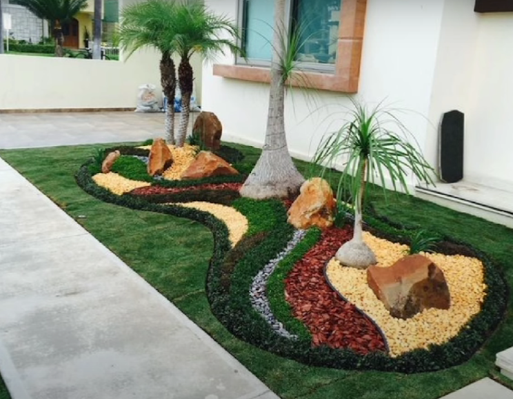 Decorative rock and mulch garden bed with palms