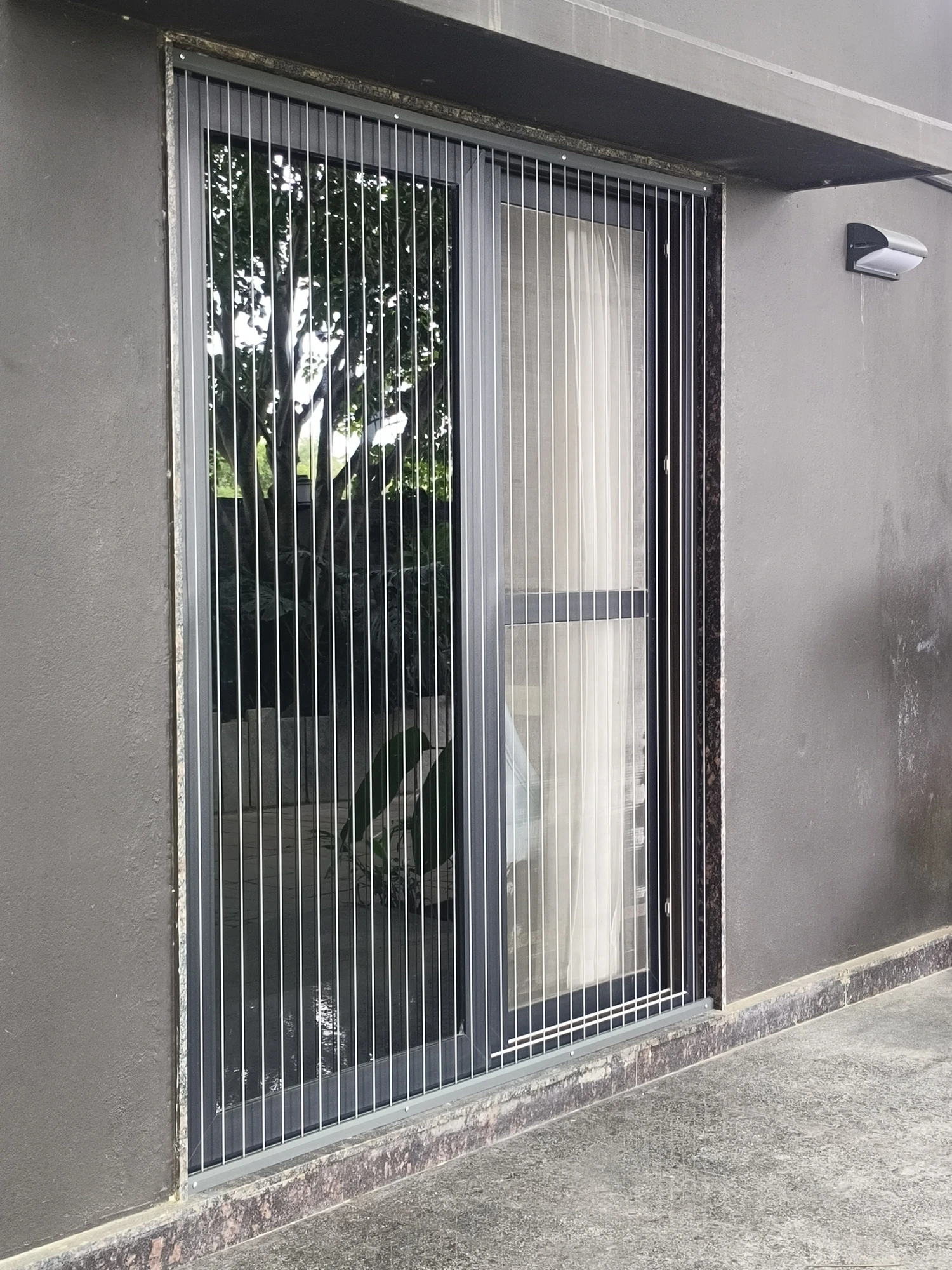 Sliding glass door of a Bengaluru home fitted with PR invisible grill cables in a neat grey track, with the sliding shutter still free to open