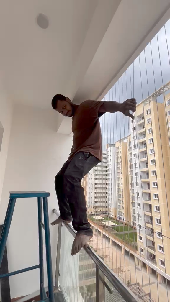 PR Invisible Grill technician standing on the installed stainless steel cables of a high-rise apartment balcony in Bengaluru during an on-site load check