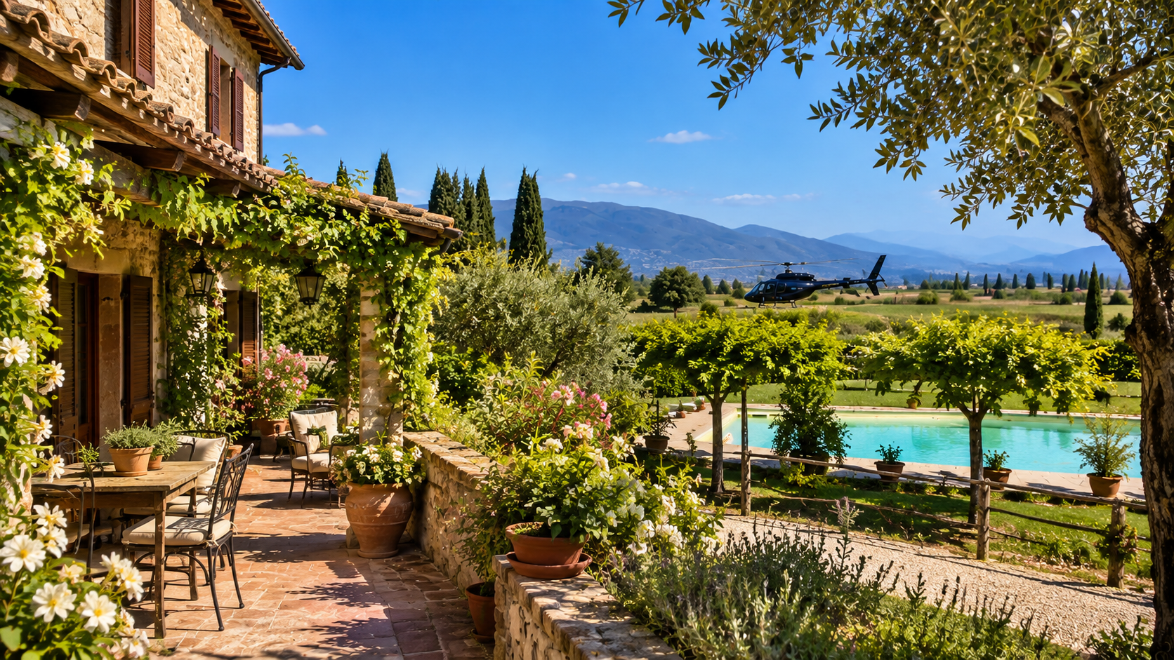 La terrazza del casale con pergola fiorita, piscina ed elicottero sullo sfondo